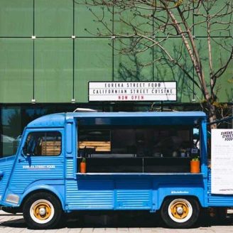 One of the customized food trucks from Jerusalem Company is blue and parked in front of a building