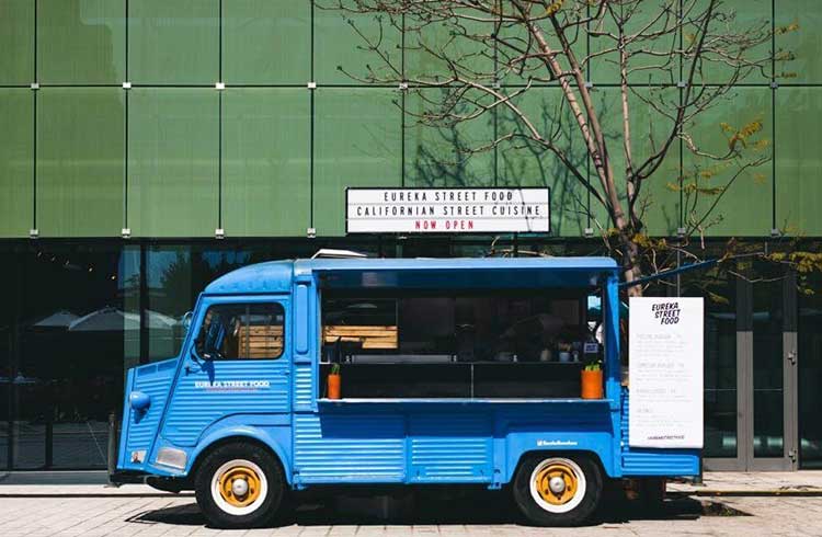One of the customized food trucks from Jerusalem Company is blue and parked in front of a building