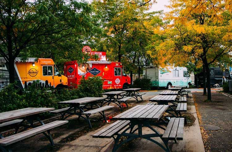 Three food trucks are lined up in front of the garden, which contains a number of chairs and tables