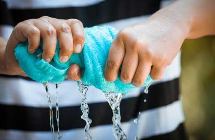 A young man squeezes water out of a towel