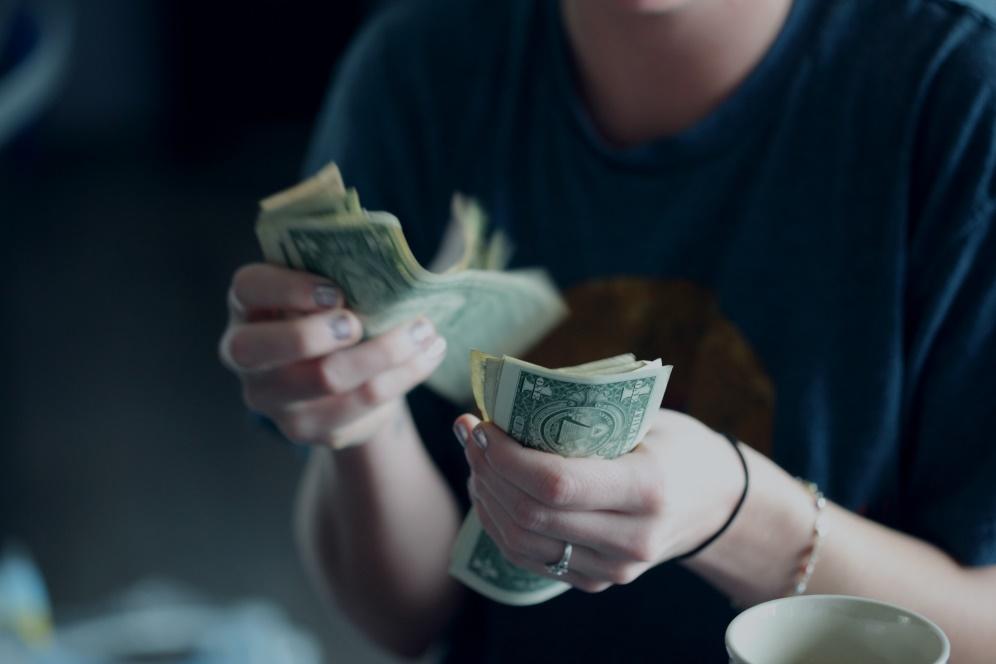A girl wearing a blue sweater is counting money