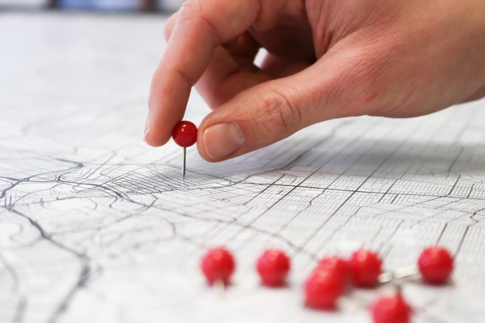 A person identifies a location on a map using a red pin