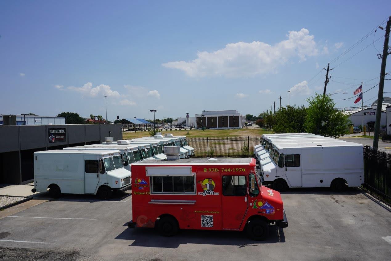 A group of food trucks for sale made by Jerusalem line up in front of the Jerusalem custom food trucks & trailers building in Houston