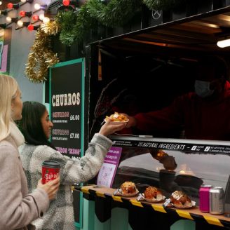 Two girls, one brunette and one blonde, order two meals from a colorful food truck ( Food Truck Customers )