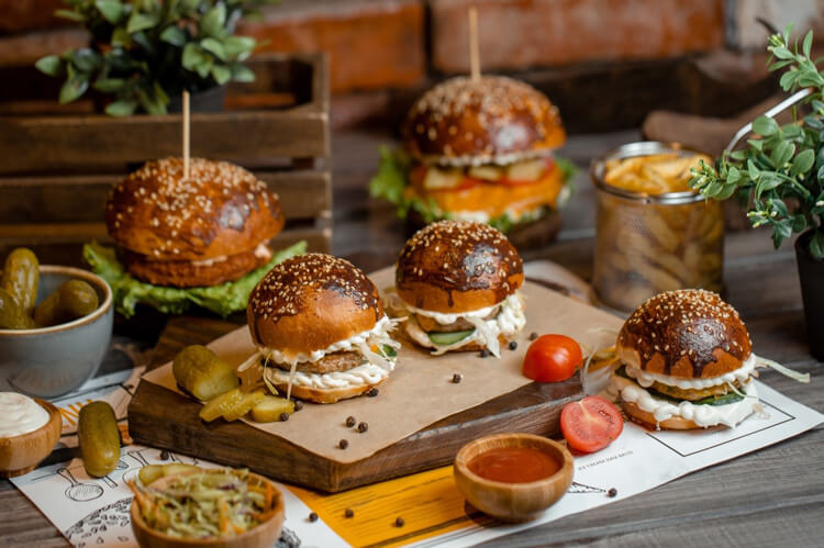 Four slider hamburger sandwiches of different sizes