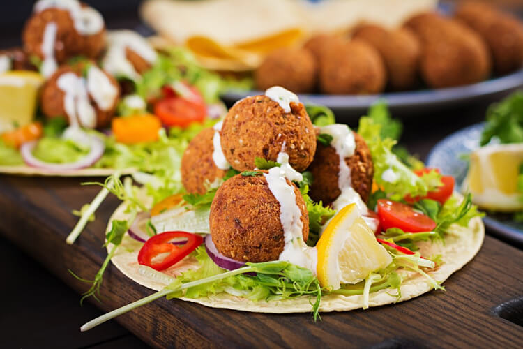 A plate of falafel decorated with lemon and vegetables