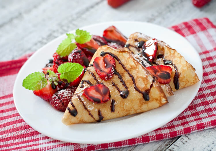 Crepe with pieces of strawberries and liquid chocolate