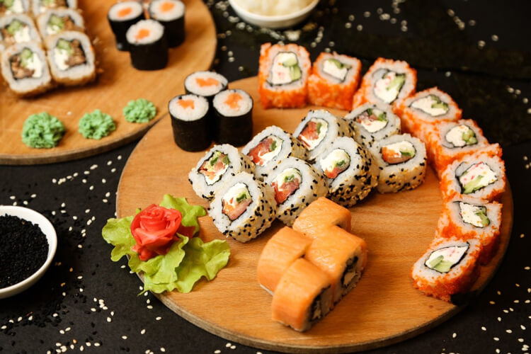 Pieces of sushi with lettuce and tomatoes in a wooden tray