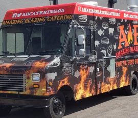 Amazing Blazing Catering food truck with a black wrap featuring realistic flame graphics along the lower body, white food and animal silhouettes, bold ABC logo, "You've Just Been Blazed" tagline, red header stripe with social media handles, and phone number