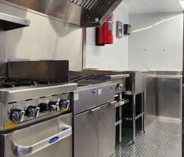 Food trailer kitchen interior featuring a CookRite four-burner range with oven base, flat-top griddle, stainless steel exhaust hood, fire suppression system, under-counter storage, and diamond-plate flooring