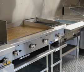 Commercial food truck cooking line showing a gas range, CookRite flat-top griddle, deep fryer, and under-counter refrigerator unit lined up on diamond-plate flooring