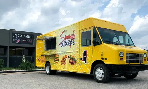 Sammy's Burgers food truck wrapped in a bright yellow sunburst design with large food illustrations including a burger and wings, open service window, parked outside JRS Custom Inc