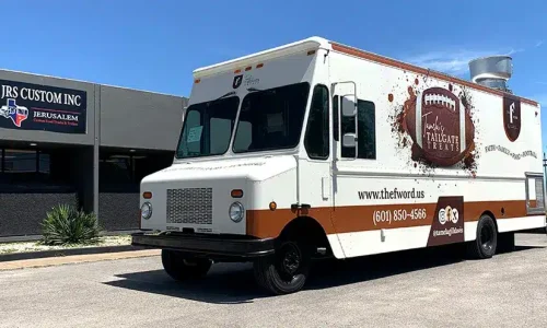 Tamela's Tailgate Treats food truck with a white and brown wrap featuring a football graphic, the tagline "Faith, Family, Food, Football," website, and phone number, parked outside JRS Custom Inc