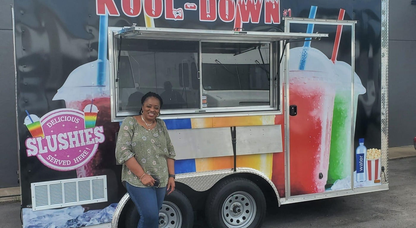 Kool-Down slushie food trailer owner posing in front of her custom built trailer with colorful frozen drink wrap graphics
