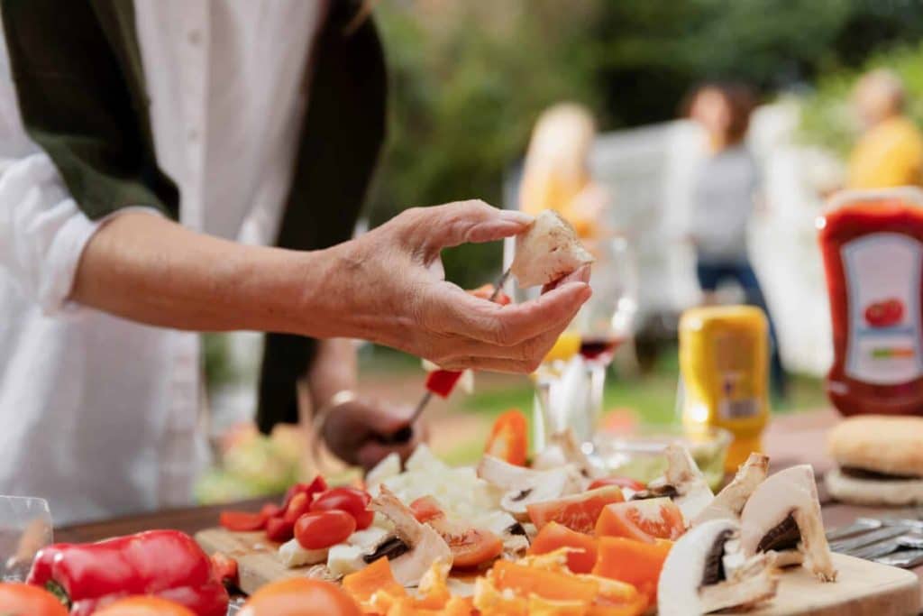 hand holding a piece of mushroom over a cutting board of other vegetables