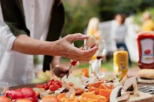 hand holding a piece of mushroom over a cutting board of other vegetables