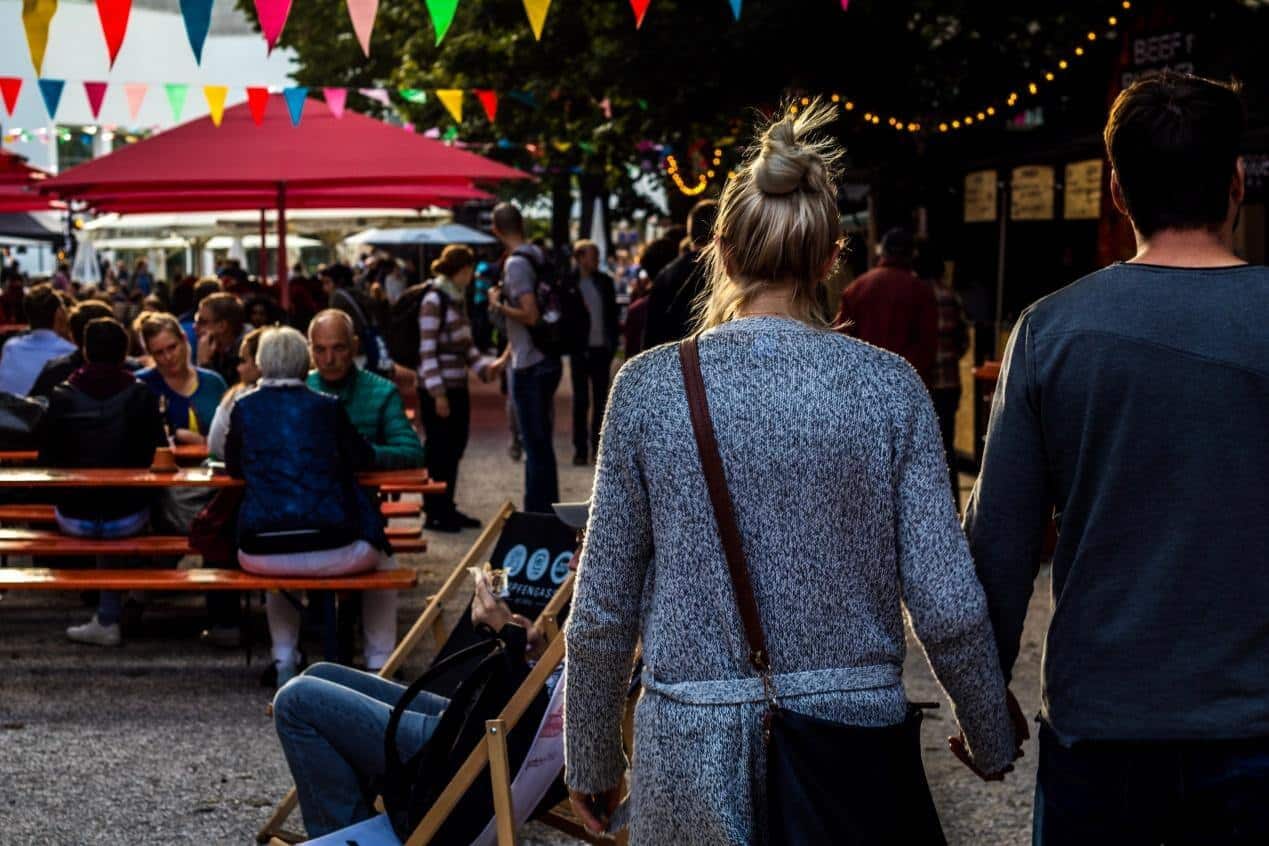 A young man and a girl holding hands and walking at a festival