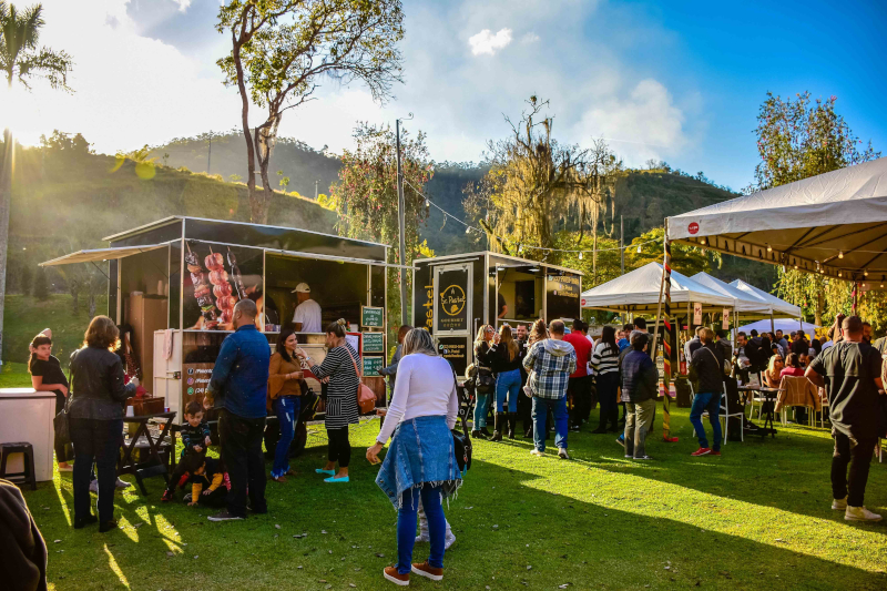 Crowd of customers browsing food trucks at an outdoor food truck park event on a sunny day