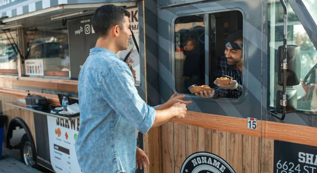 Food truck operator handing an order to a customer through the service window