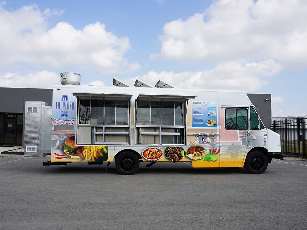 La Plaza Food truck with a white and gold wrap featuring large menu photos of Mexican dishes, multiple service windows with awnings open, and contact information on the side
