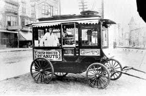 Vintage black and white photograph of an early 1900s street food cart selling fresh roasted peanuts and buttered popcorn