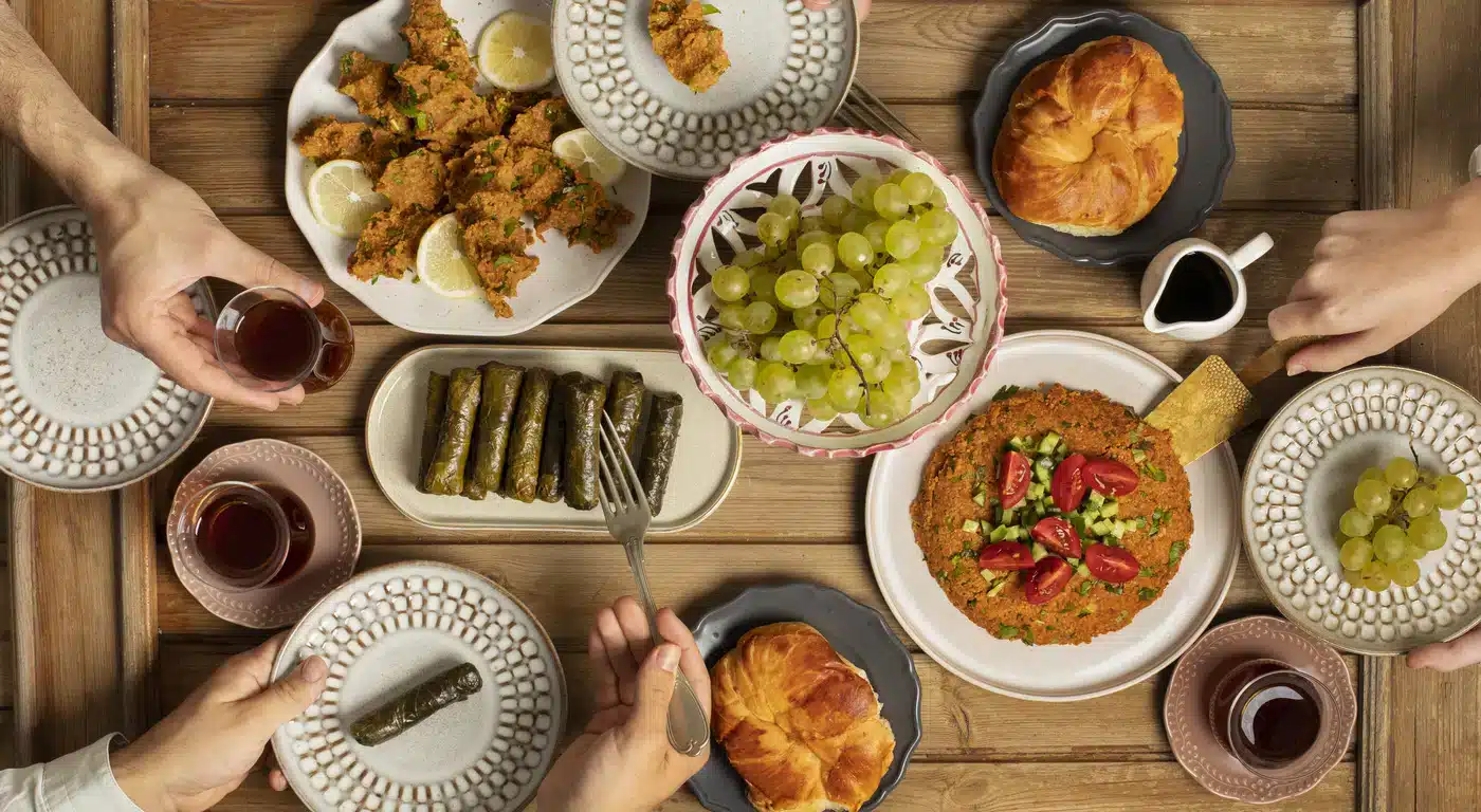 Overhead view of a shared Middle Eastern meal with dolmas, grapes, spiced dishes, bread, and tea