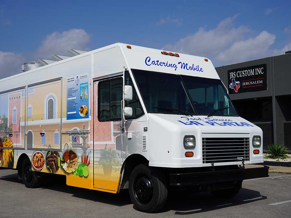 La Plaza Food truck with a white and gold wrap featuring large menu photos of Mexican dishes, multiple service windows with awnings open, and contact information on the side outside the jrs office