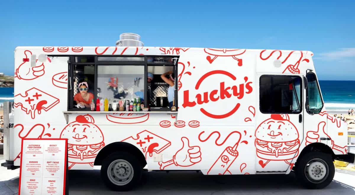lucky's white and red food truck parked at a beach
