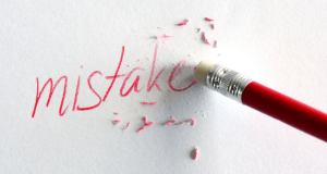 pencil erasing the word mistake written on a white wall