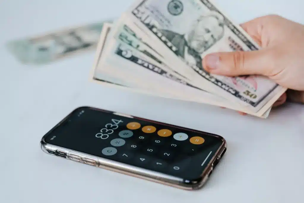 hand holding cash next to a calculator on a white table