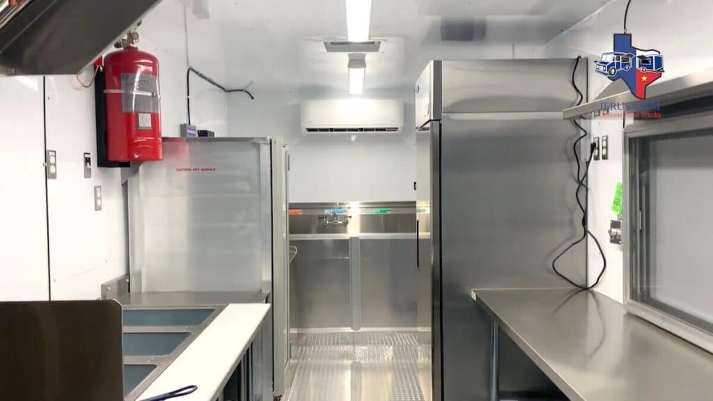 Interior of a custom concession trailer build by JRS Custom Food Trucks and Trailers showing stainless steel equipment and refrigeration