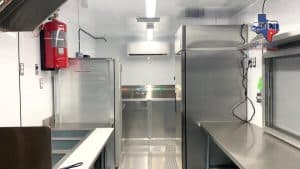 Interior of a custom concession trailer build by JRS Custom Food Trucks and Trailers showing stainless steel equipment and refrigeration