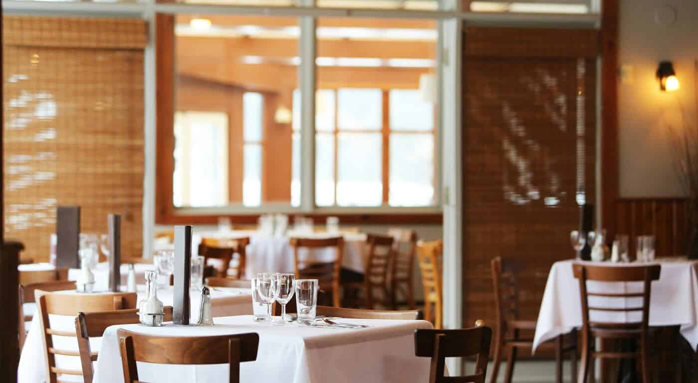 restaurant dining room with chairs, white table cloths, and dining utensils