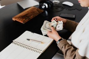 Person counting cash at a desk next to an open planner and pen