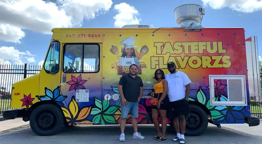 new owners and jrs rep standing in front of the newly built tasteful flavorzs food truck