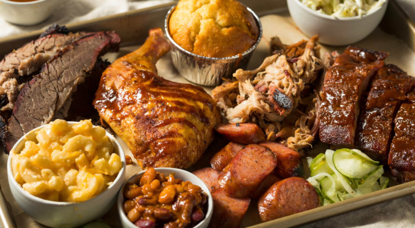 Texas barbecue spread with brisket, ribs, pulled pork, sausage, and classic sides including mac and cheese and baked beans