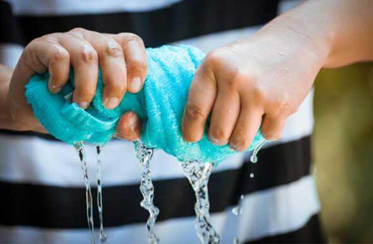 small blue towel soaked in water being rung out